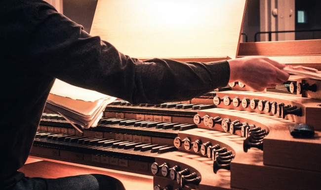 Orgelmanual von schräg unten und Hand, die Register zieht