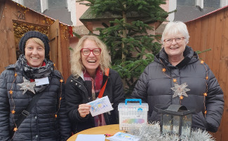 Drei Frauen in Winterkleidung zwischen Weihnachtsbuden