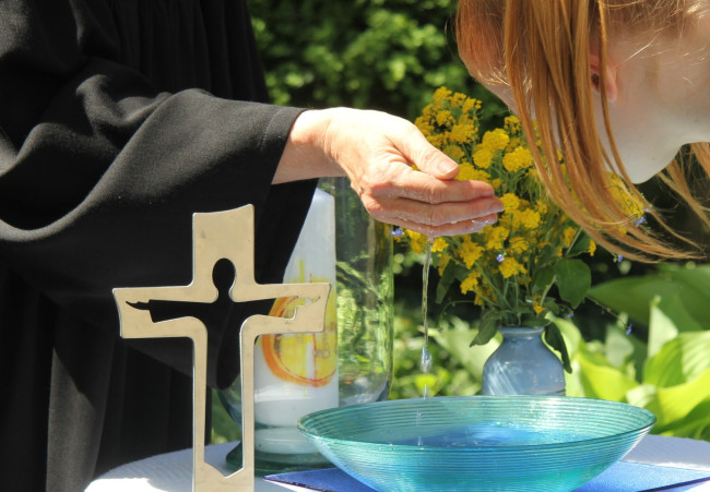 Kind mit Kopf über Taufschale im Freien