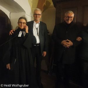 vier Personen in Sakristei von Kirche mit Telefon in der Hand